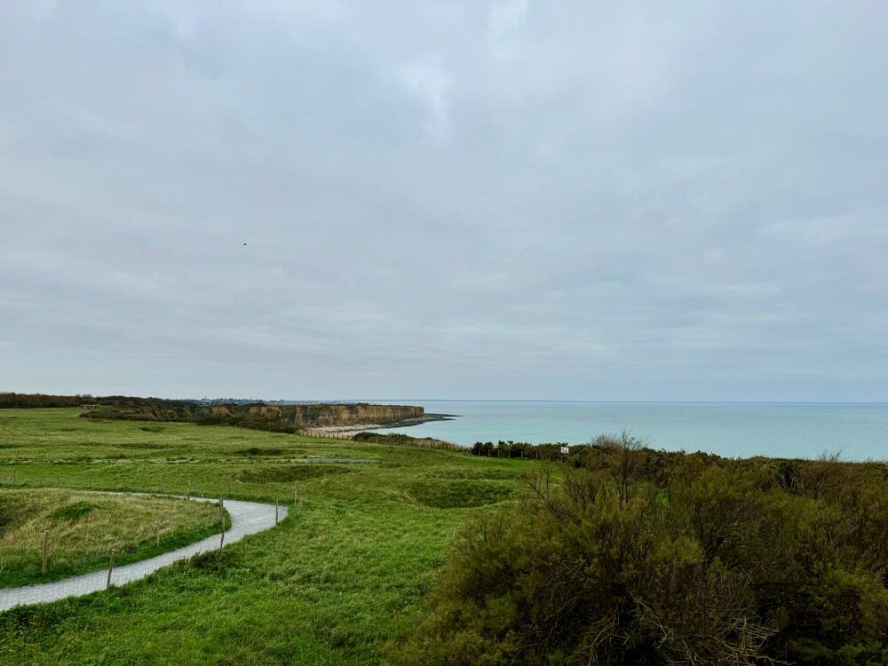 Grassy cliff top with sandy cliffs in the distance.