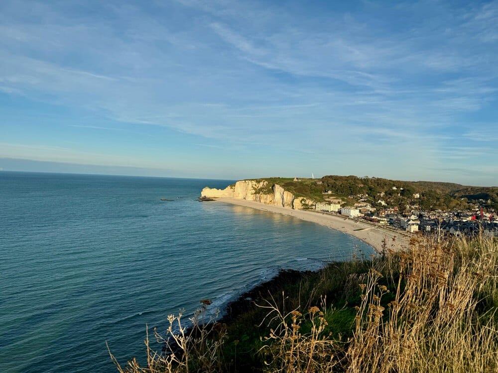 View of a seaside town and white chalk cliff topped with a small chapel