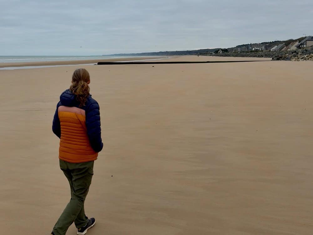 Woman walks on a large sandy beach on an overcast day