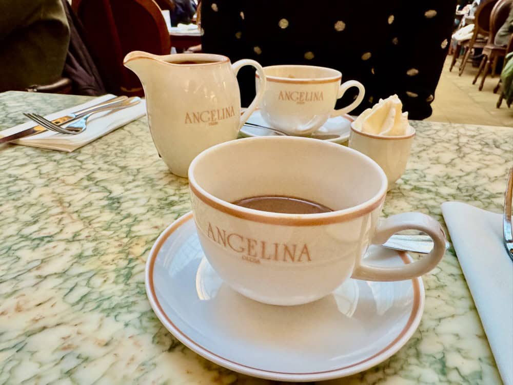 Angelina branded cups and pitchers filled with hot chocolate and whipped cream.