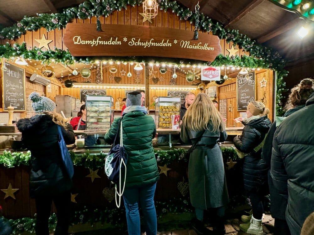 People wait in front a German Christmas market food stand