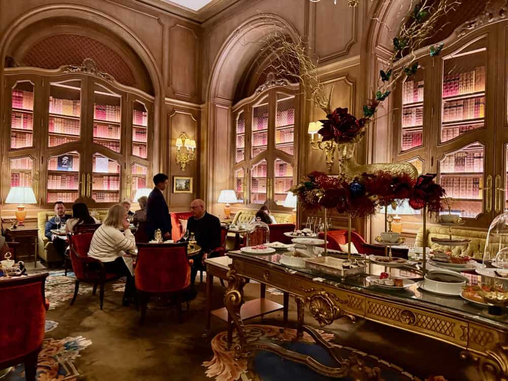 Diners sit around small tables in a Ritz lounge during afternoon tea service