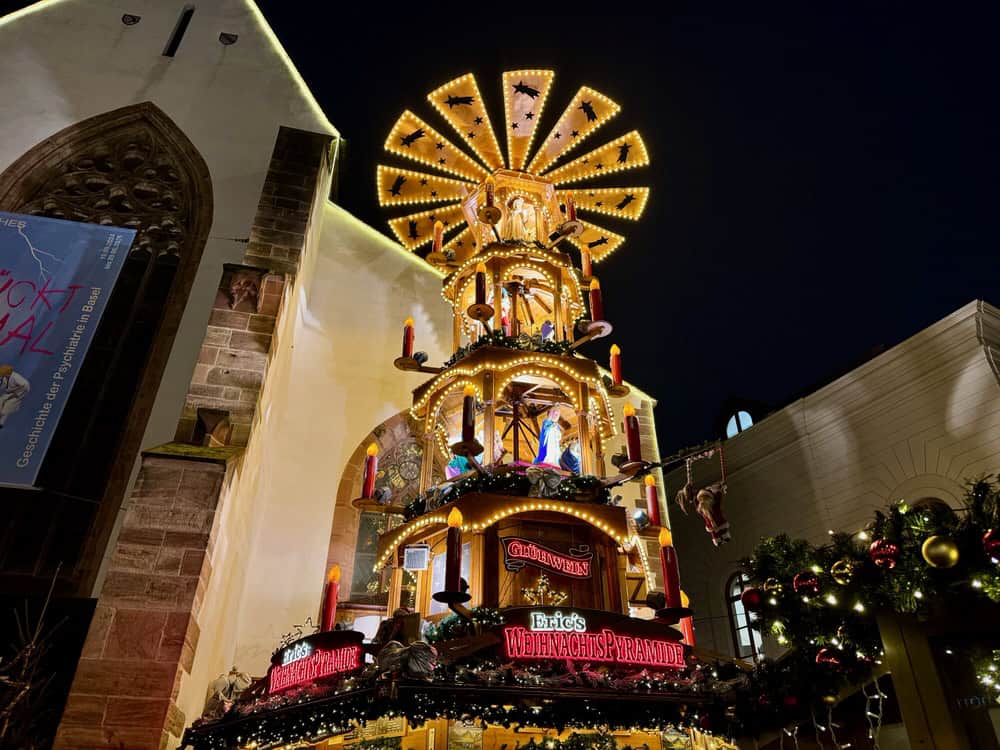 Christmas pyramid with oversized candles, statues, and windmill in the middle of a European Christmas market.
