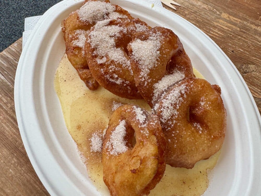 A plate of fried apple rings topped with cinnamon sugar and vanilla sauce