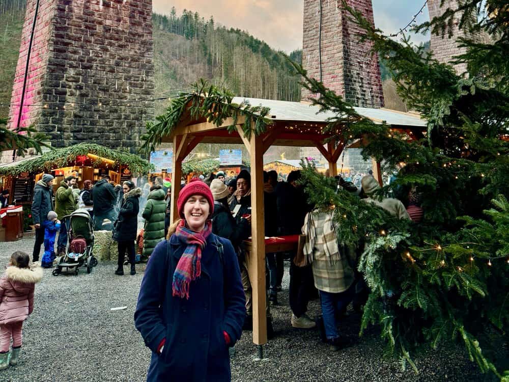Woman stands in a rural German Christmas market under a railroad viaduct in the Black Forest