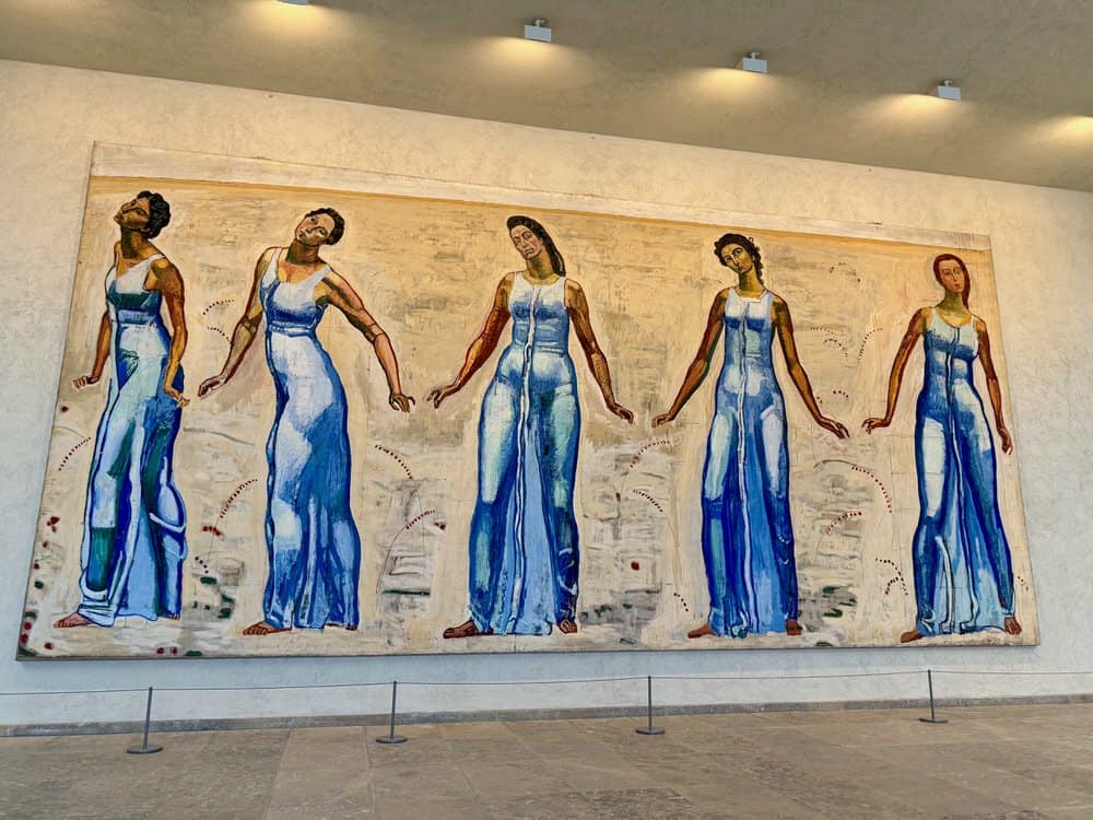 A large painting in a museum of five women robed in blue