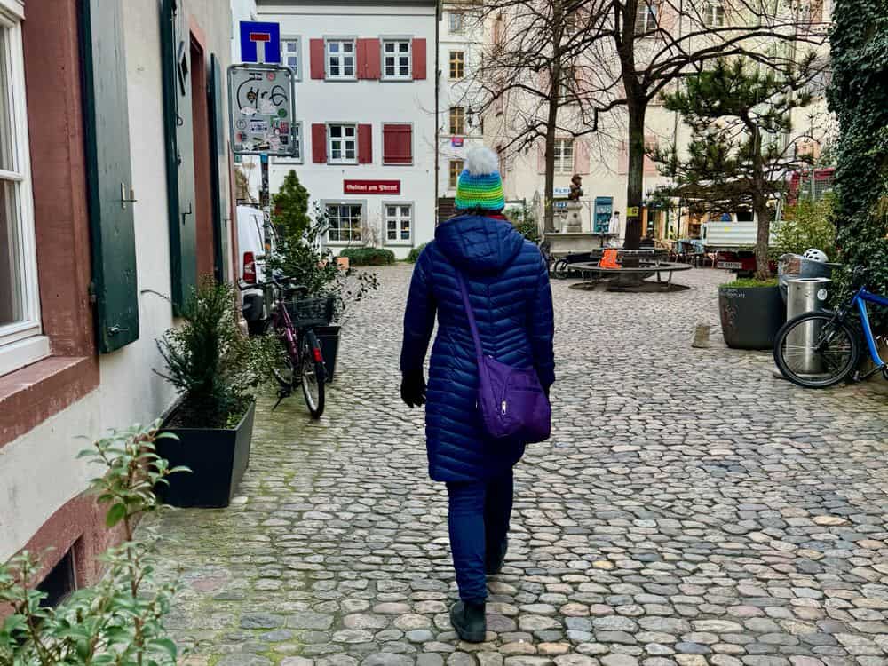 Woman dressed for winter walks on a cobblestone street in Switzerland