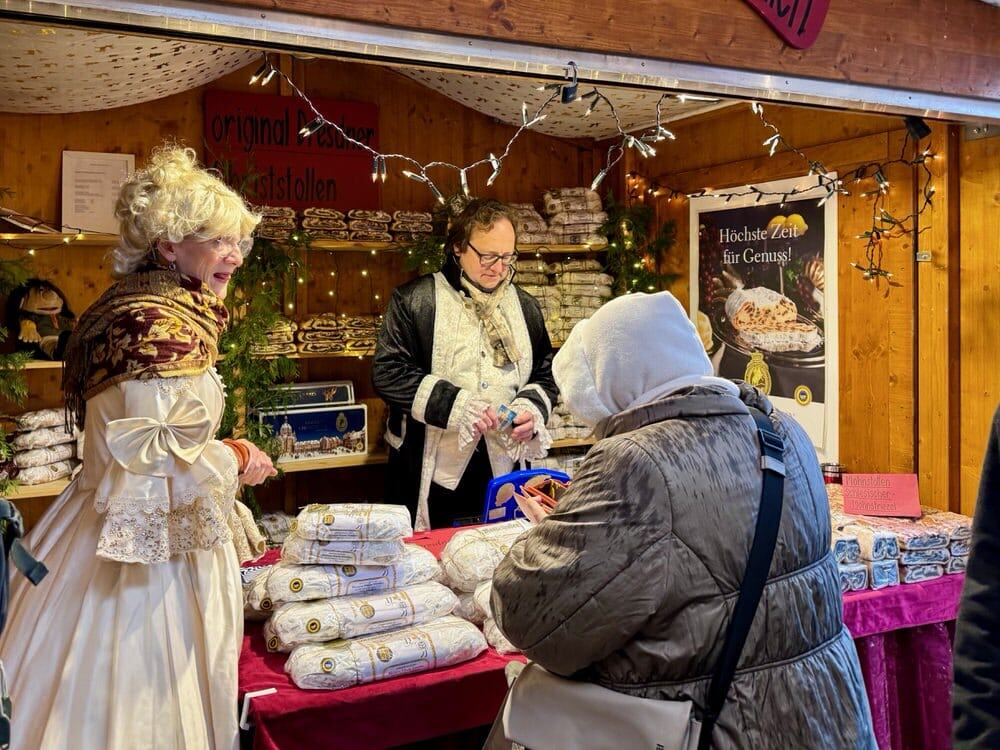 Costumed vendors sell traditional stollen bread to a woman at the Basel Christmas market