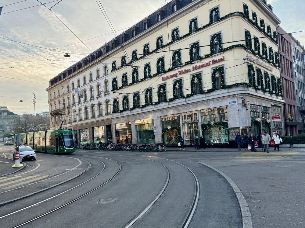 Green streetcar approaches Barfüsserplatz in Old Town Basel Switzerland in front of the Toy World Museum decorated for the holidays
