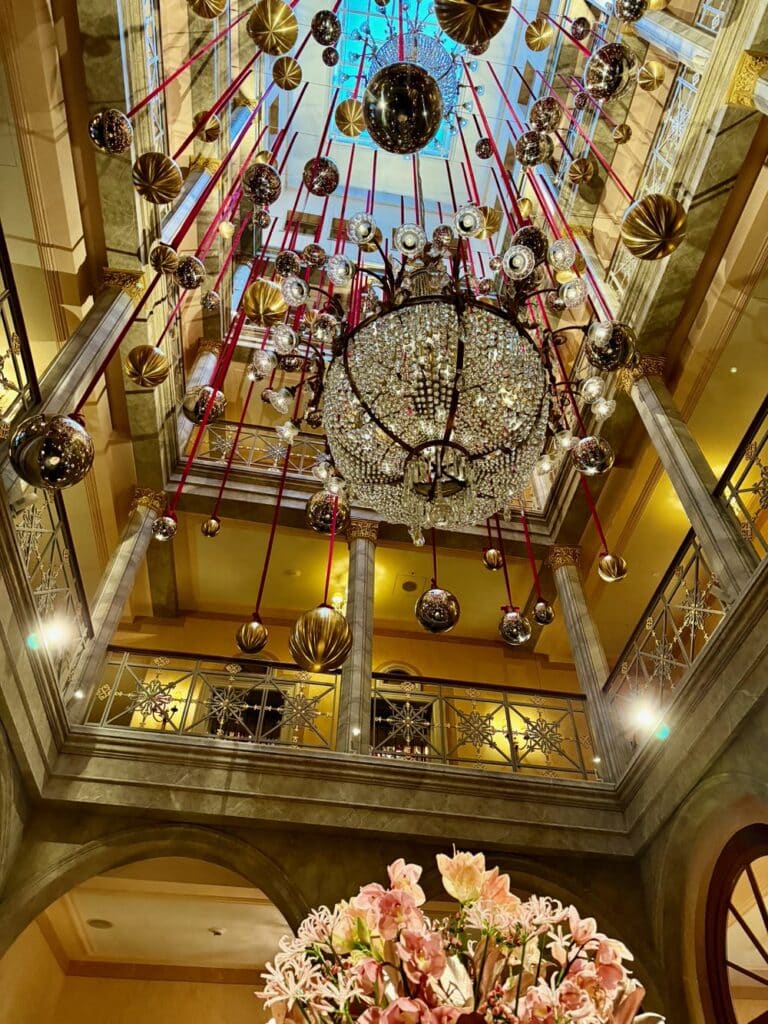 Christmas orbs and bobbles hang around a chandelier in a Swiss hotel lobby