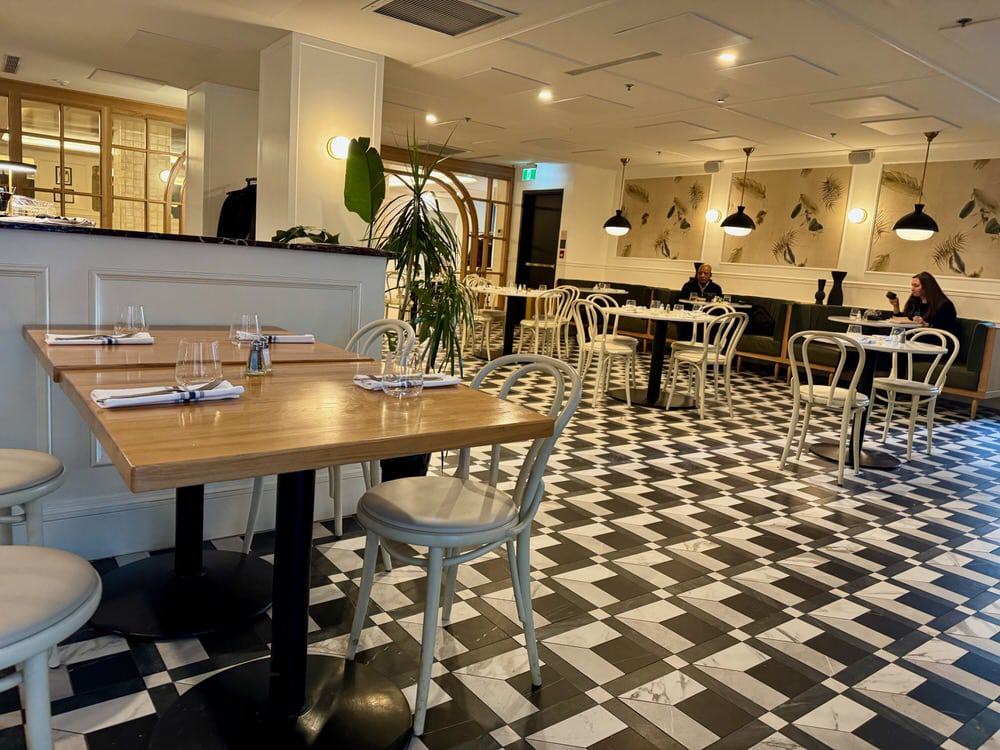 A mostly empty dining room with a black and white tile floor at breakfast