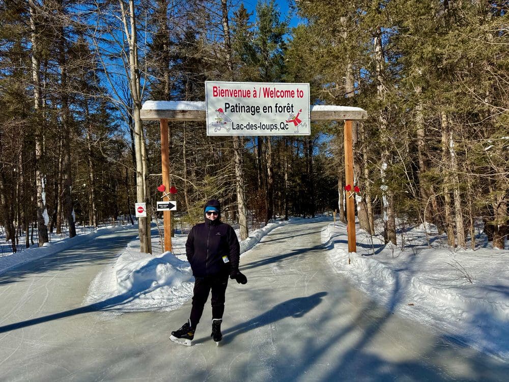 Woman poses at the entrance to a skate trail in Quebec forest