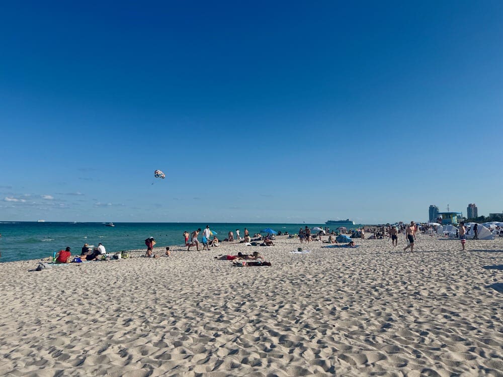 Beachgoers lounge and recreate on the sandy expanse of Miami Beach in front of Biscayne Bay