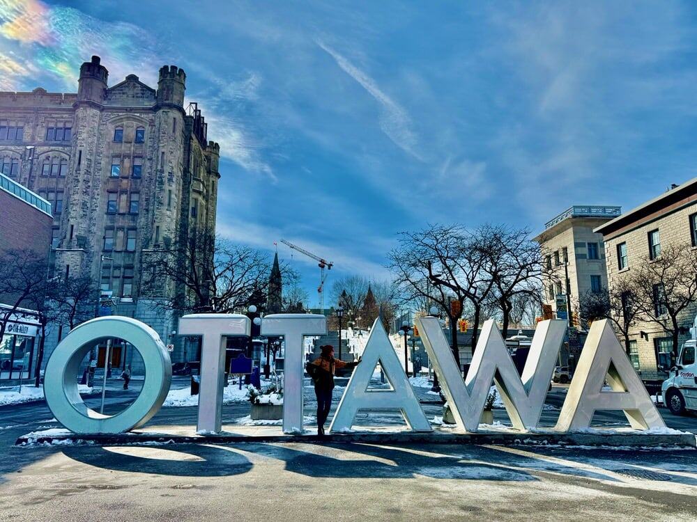 Woman poses inside the light up Ottawa letter sign in ByWard market during winter