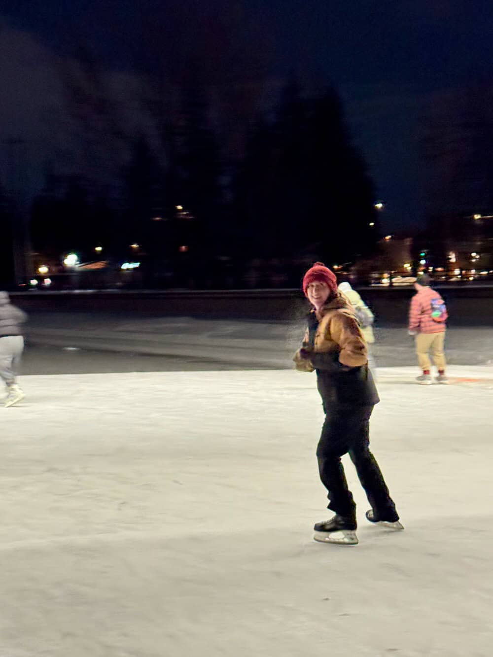 Woman in winter gear skates on the Rideau Canal after dark