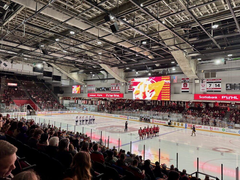 Starting lineups of professional women hockey players stand for the national anthems at a PWHL game in Ottawa