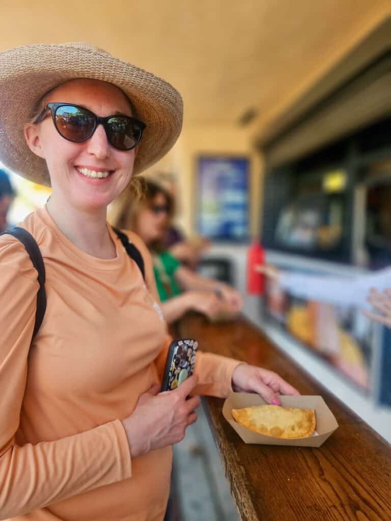 Woman holds out a Cubano empanada at an outdoor food counter in Little Havana in Miami