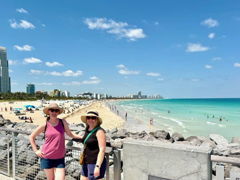 Two woman wearing sunhats standing in front of busy South Beach on a sunny day