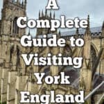 Elevated view of York Minster front two towers as seen from the transept roof. Text overlay reads "A Complete Guide to Visiting York England"