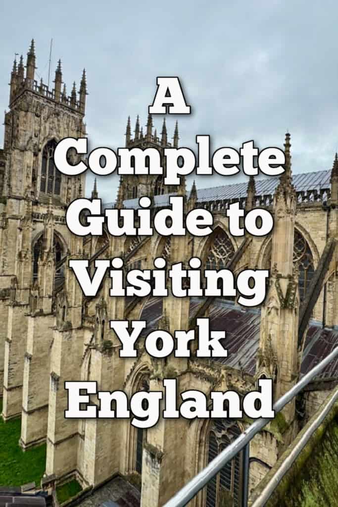 Elevated view of York Minster front two towers as seen from the transept roof. Text overlay reads "A Complete Guide to Visiting York England"