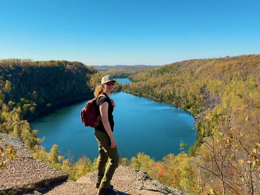 Woman stands on top of a cliff overlooking two lakes