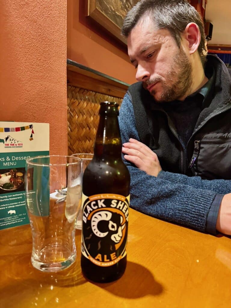 A man sits behind a bottle of Black Sheep amber ale at a restaurant