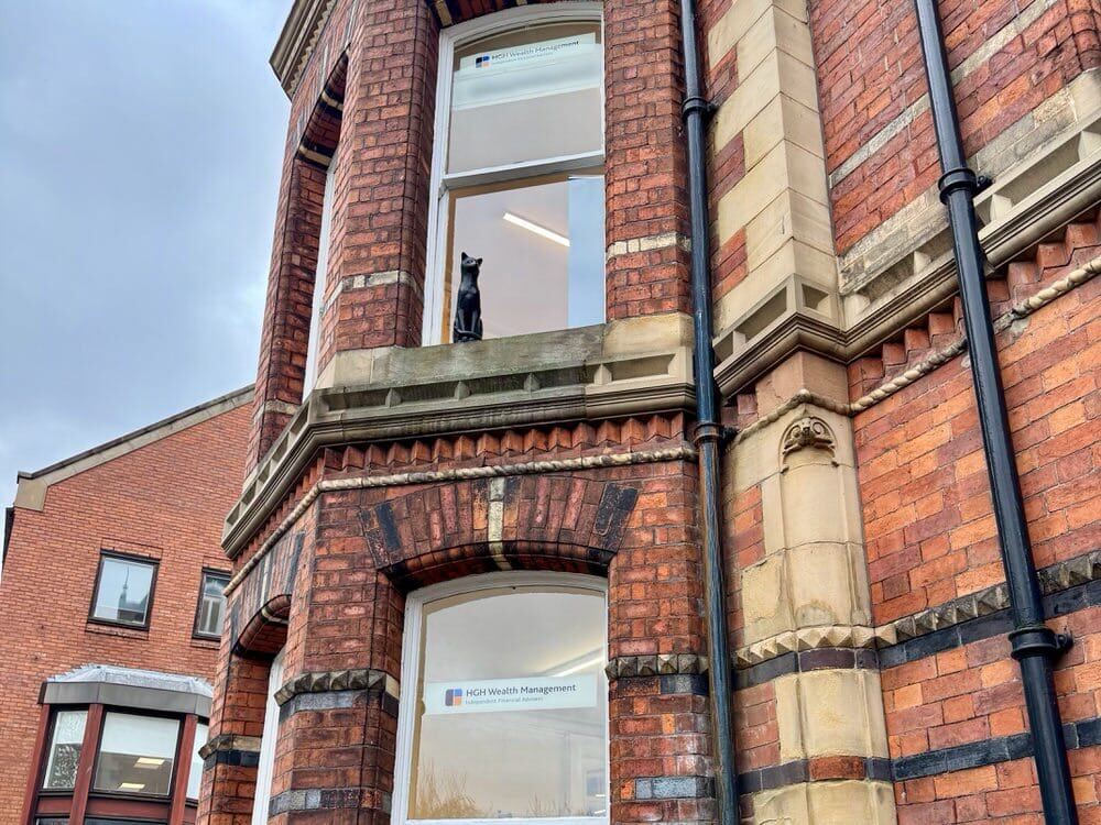A black cat statue sits on an upper story window sill on an office building in York City
