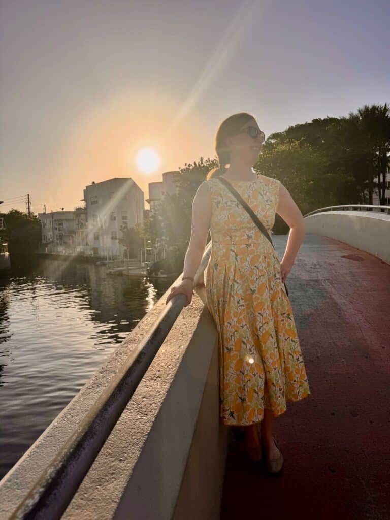 Woman in a sundress poses on a bridge over a small canal in Miami