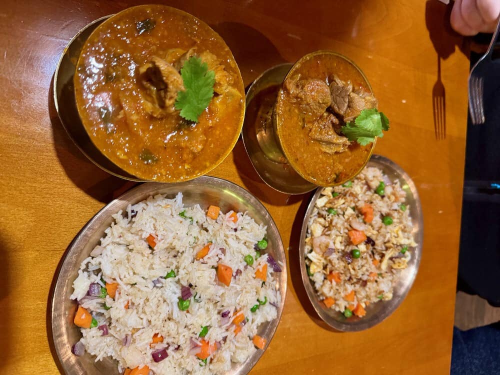 Two Nepalese curries with rice side dishes on a restaurant table