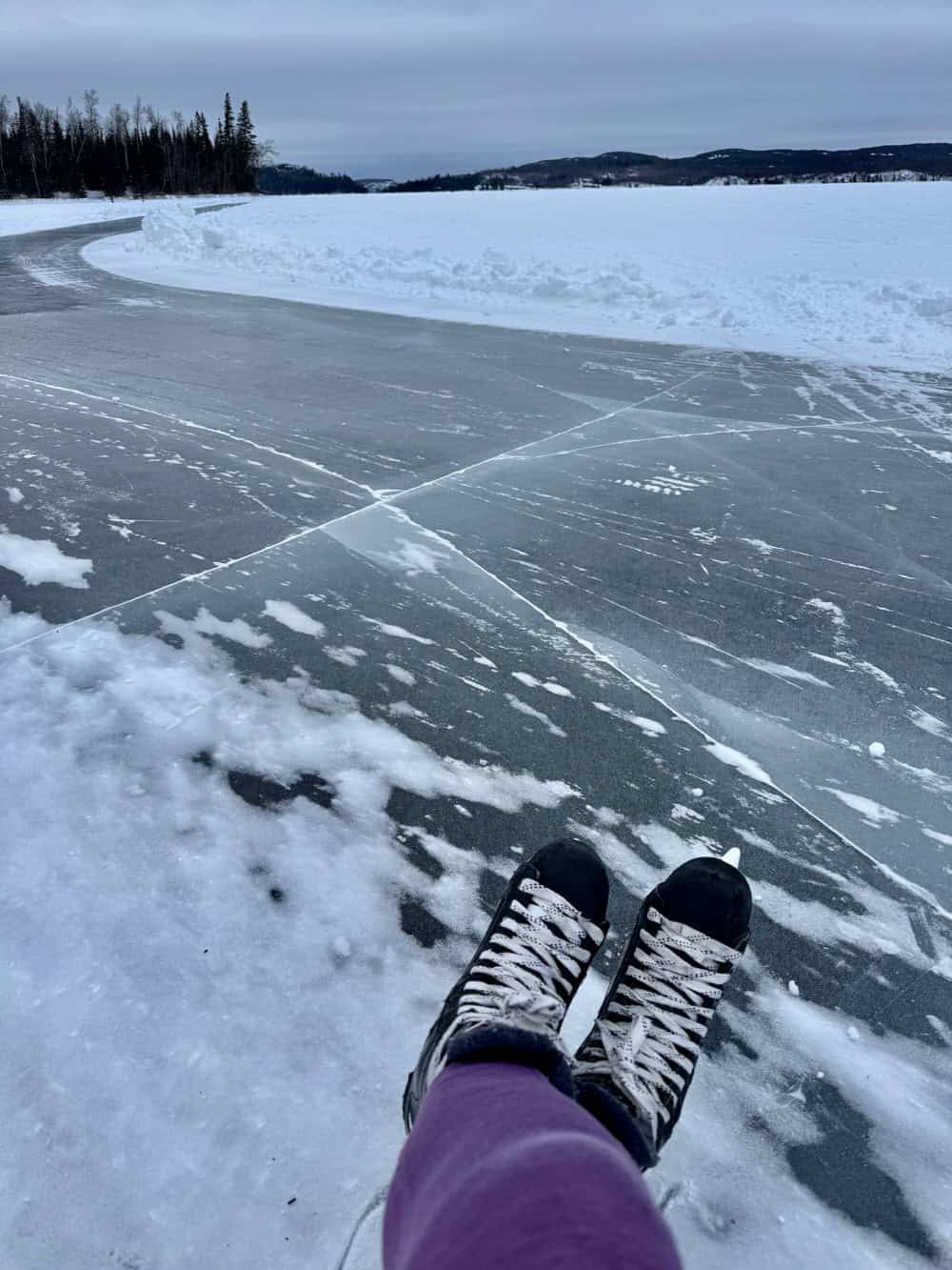 First person view of skates in front a northern Minnesota skating trail