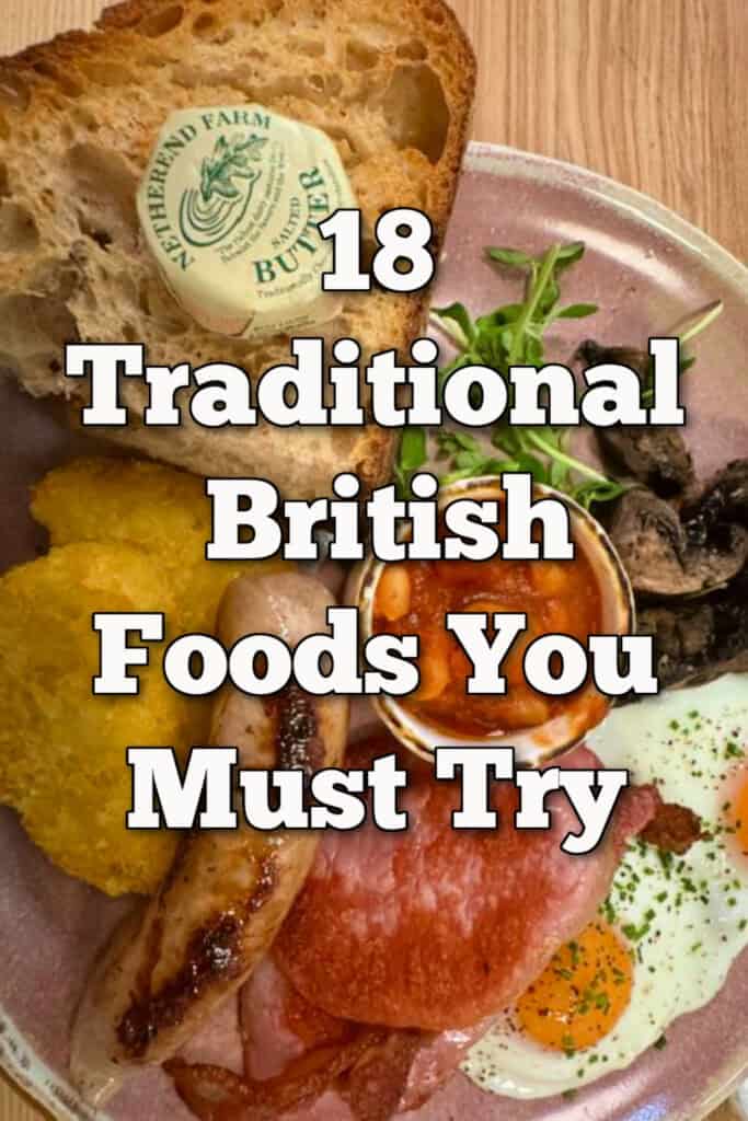 A breakfast plate of traditional British breakfast items including eggs, sausage, toast, bacon rashers, and baked beans. Text overlay reads "18 Traditional British Foods You Must Try."