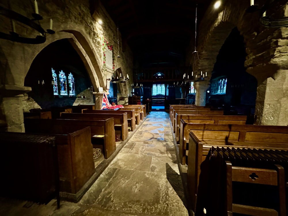Interior of a stone medieval English church with wooden pews