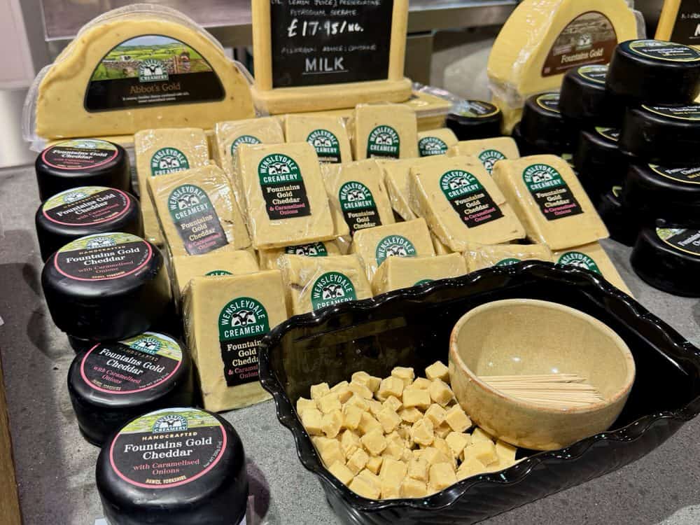 Samples of cheese and packaged ready to buy blocks of cheddar cheese sit on a store counter