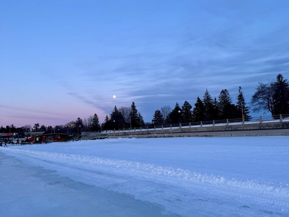 A full moon hangs over the skateway at sunset in February