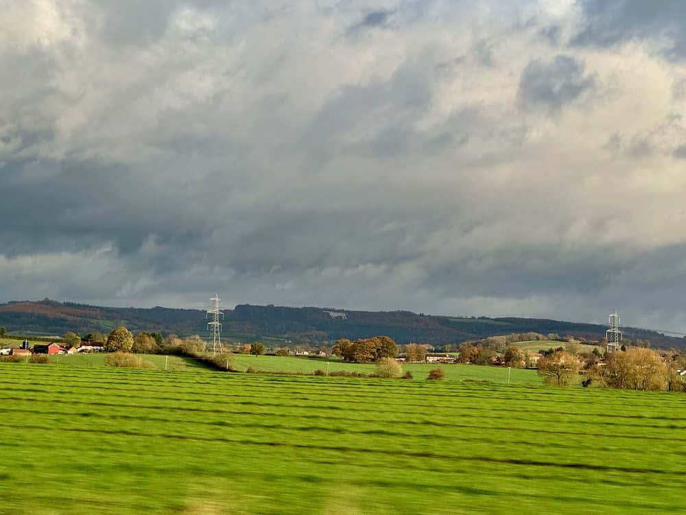 Green field with the North York Moors and the Kilburn White Horse in the background as seen from a car