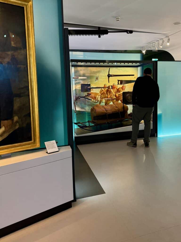 Man looks inside a glass display case showcasing an arctic sled at the National Maritime Museum Greenwich