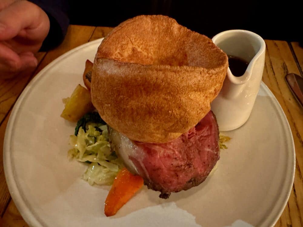 A pub serving of sunday roast with prime rib, cabbage, veg, Yorkshire pudding, and gravy