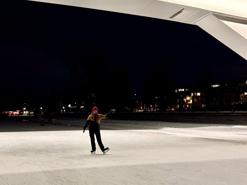 Woman poses under a lighted bridge on the frozen Rideau Canal in central Ottawa, Ontario