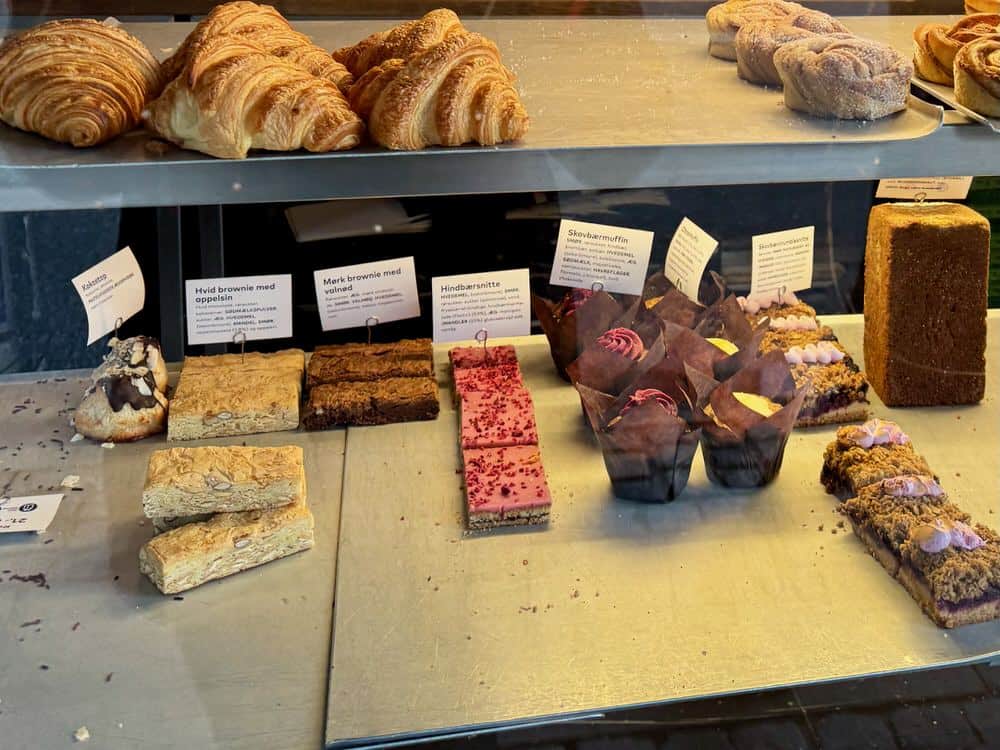 Tray bakes and muffins in a Copenhagen bakery case including raspberry squares