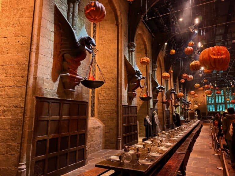 Gargoyles line the walls of the Great Hall set from Harry Potter films. Carved pumpkins hang in the air.