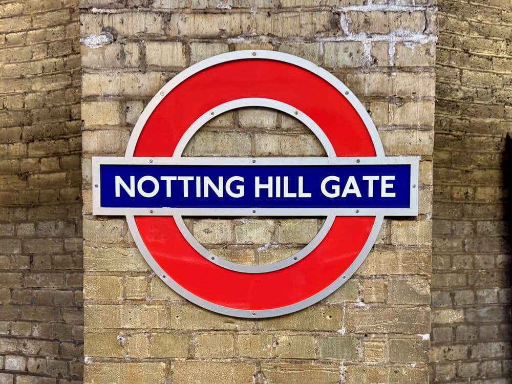 A red and blue station sign in the Notting Hill Gate London underground station
