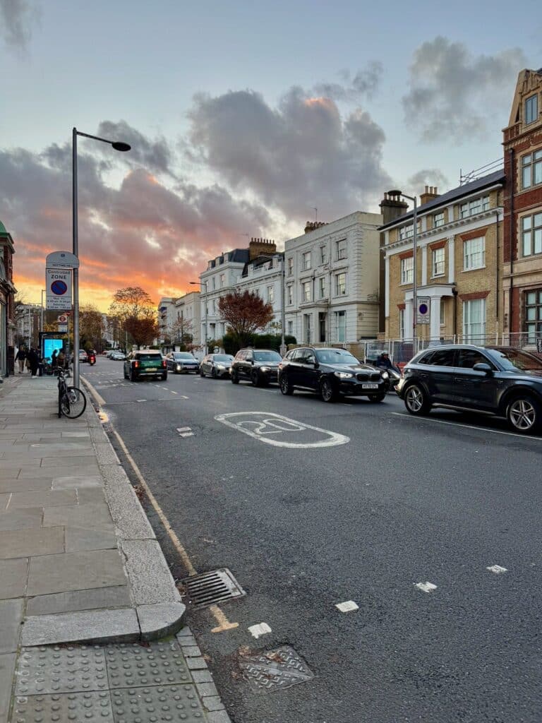 The sunsets over a line of cars at a London stoplight in Notting Hill