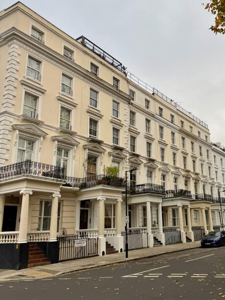 Identical terrace houses with columned entrances line a London street in Notting Hill