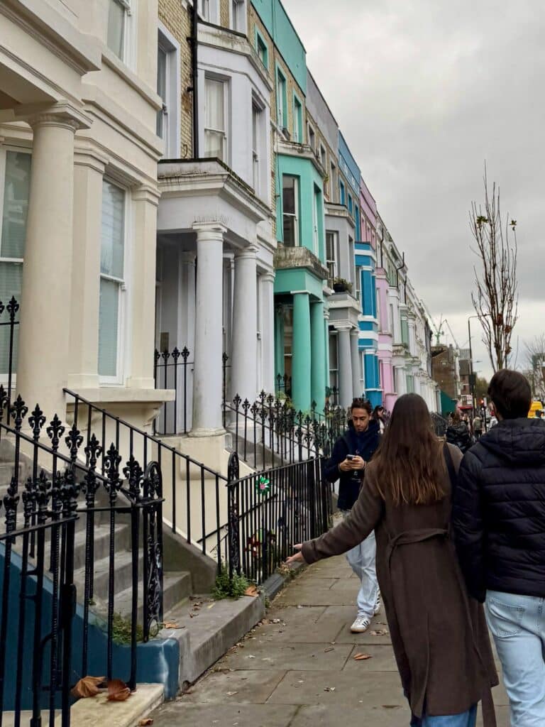 People stroll in front of colorful house facades in Notting Hill London