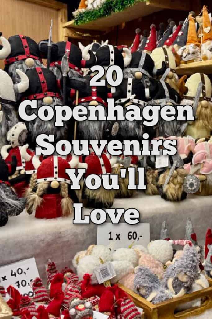 A Christmas market booth stuffed full of nisse figurines (gnomes) of various sizes and colors. Text overlay reads "20 Copenhagen Souvenirs You'll Love"