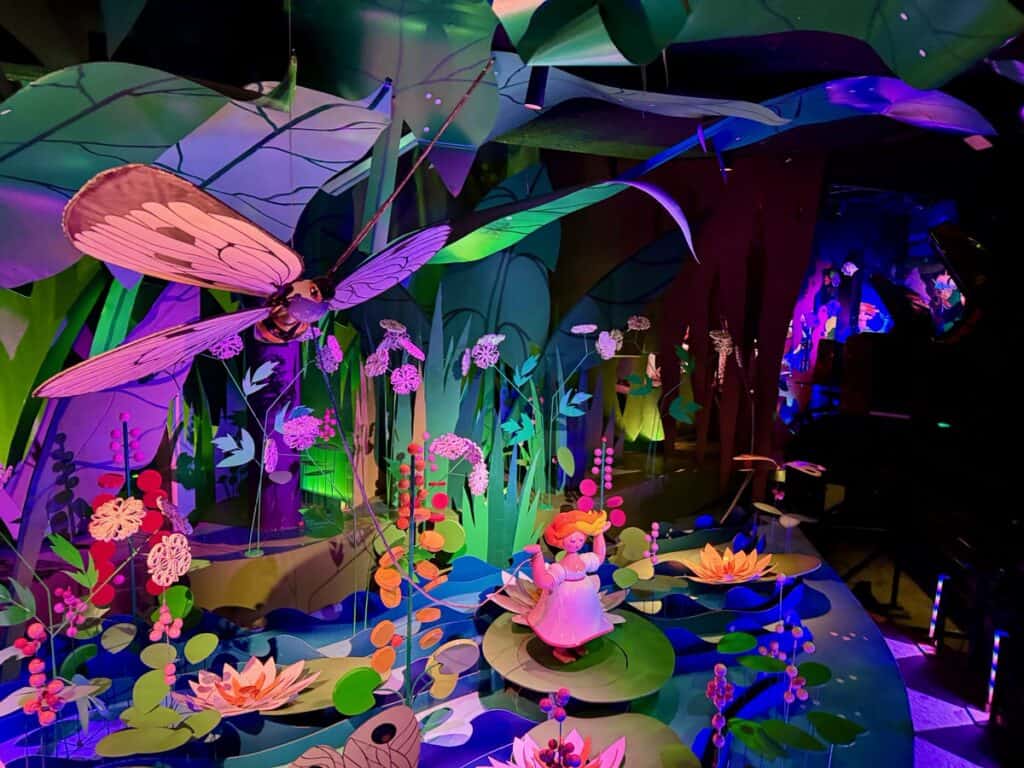 Colorful figurines including a tiny girl, a dragonfly, and flowers in the Thumbelina scene of the Tivoli Gardens Flying Trunk ride