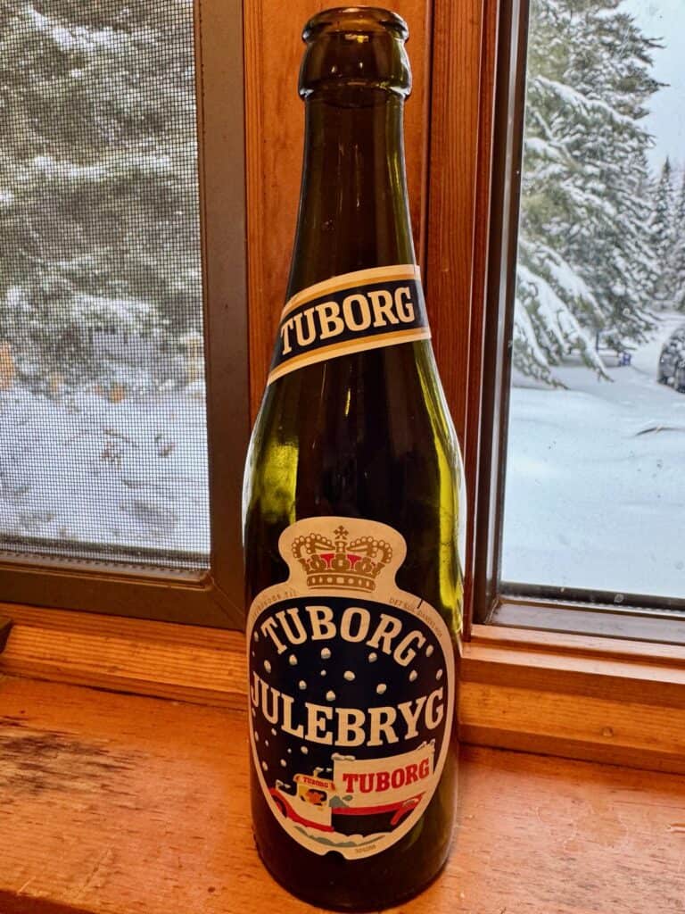 Bottle of Carlsberg julebryg featuring a retro label with a cartoon of a Carlberg truck driving through a snow storm.