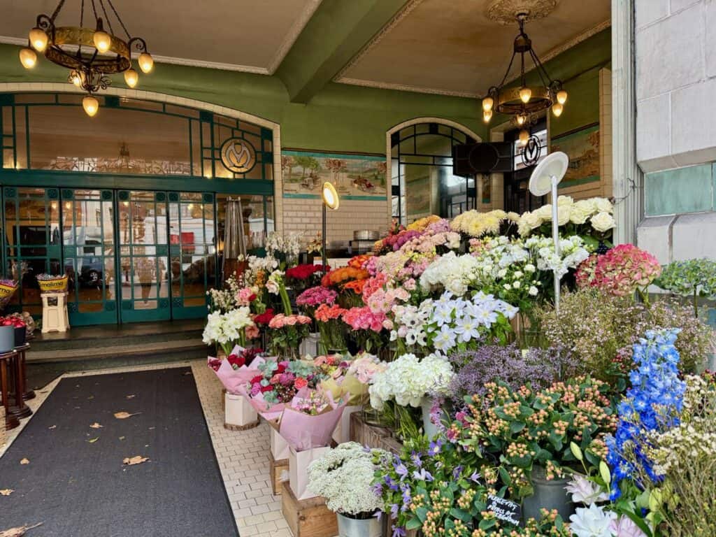 A large assortment of colorful cut flowers line the entrance to a business in South Kensington London