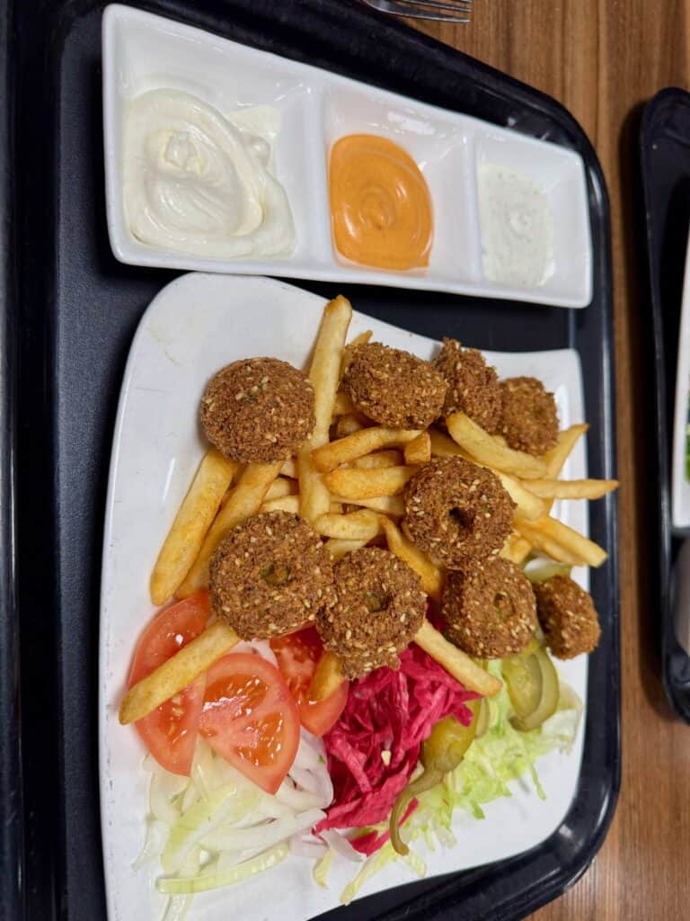 Tray of falafel, French fries, salad, and dipping sauces