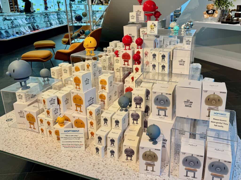 Boxes of various sized Hoptimist Danish desk figurines cover a gift shop table.